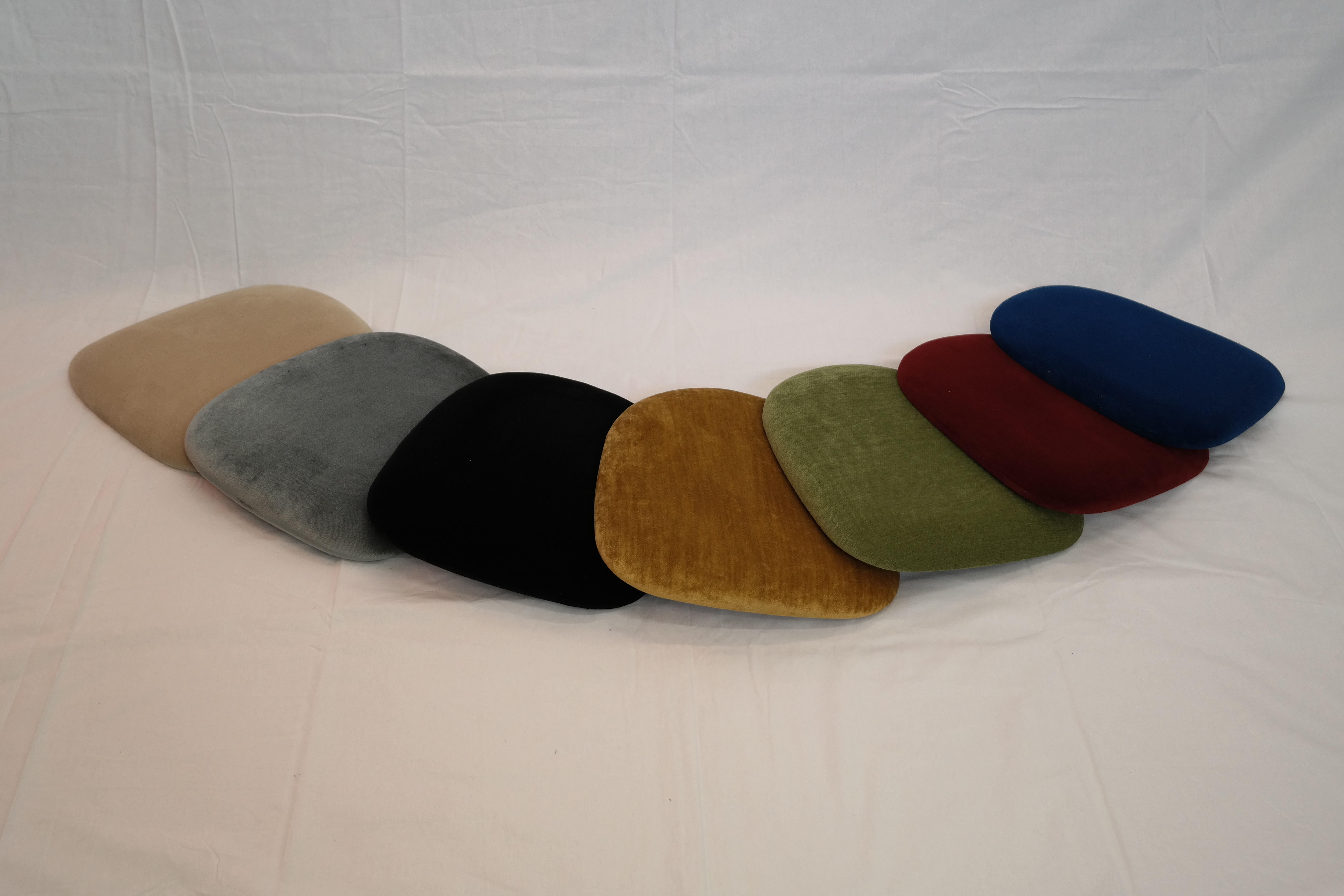 Eight shirts arranged on table in black, olive, grey, blue, white, red, mustard, and green.