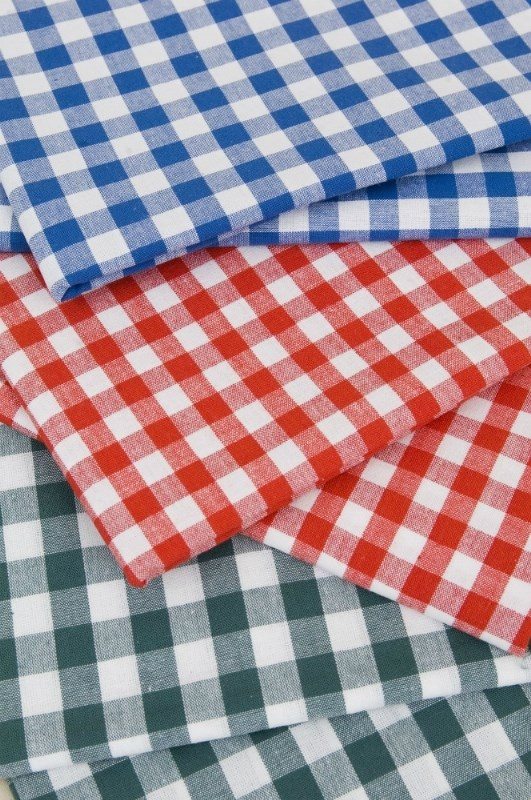 Eight shirts arranged on table in black, olive, grey, blue, white, red, mustard, and green.